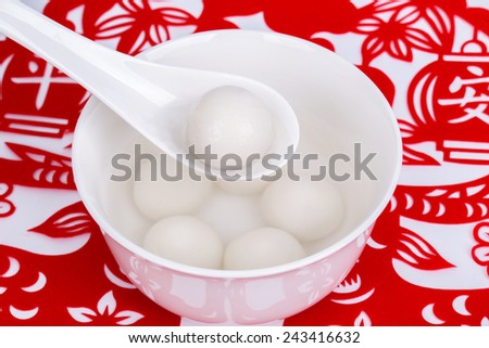 a bowl of Chinese Tangyuan on paper cut window decoration