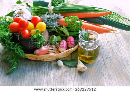 different types of fresh vegetables, carrots, tomatoes, cabbage, zucchini, herbs and olive oil in a basket