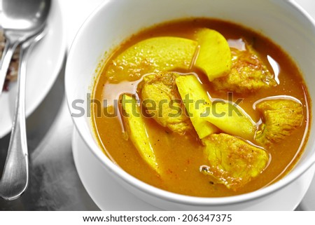 close up thai spicy yellow fish curry in white bowl