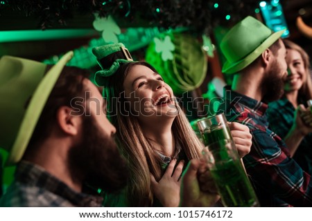The company of young people celebrate St. Patrick's Day. They have fun at the bar. They are dressed in carnival headgear. Stockfoto © 