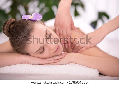Cheerful naked young woman lying on front receiving message
