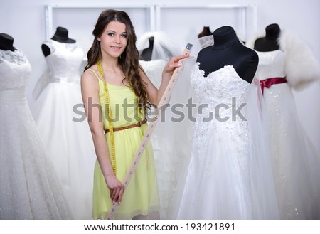 Designer wedding dresses, measures the dress on a mannequin in her shop