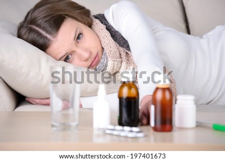 Sick woman. Young woman lying in bed while medicines laying on the foreground