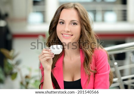 Business woman at work. Confident young business woman sitting at her working place and drinking coffee