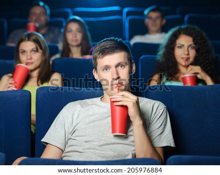 Men at the cinema. Excited young men watching movie at the cinema and drinking soda