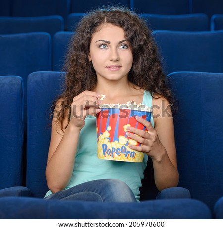 Women at the cinema. Beautiful young women eating popcorn while watching movie at the cinema