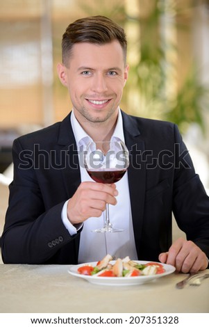 The elegant man in a business suit, drinking wine, sitting in a restaurant