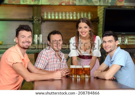 Beer for gentlemen. Beautiful young waitress serving beer while three men sitting at the table in beer pub