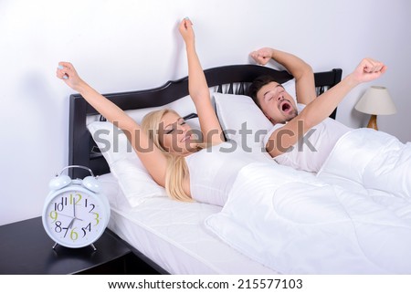 Good morning! Young couple wake up in the morning in her bedroom, lifting your hands up