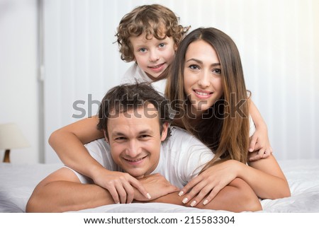 Happy family looking at the camera on their bed