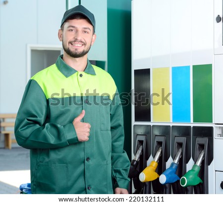 Smiling worker at the gas station, while filling a car