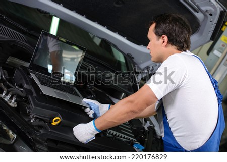 Professional mechanic using a laptop computer to check a car engine