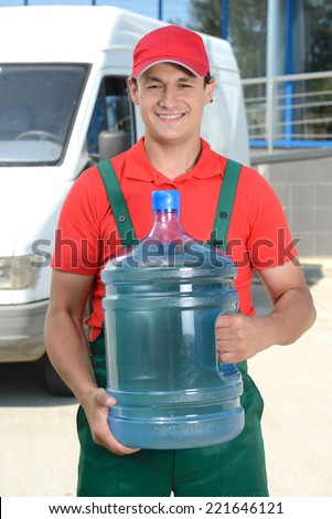 Smiling young male delivery courier man in front of cargo van delivering bottles of water