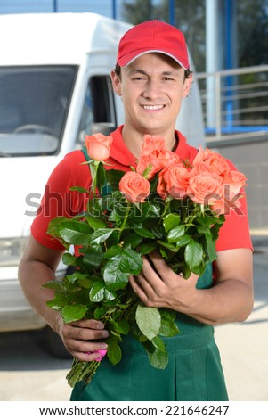 Smiling young male delivery courier man in front of cargo van delivering flowers