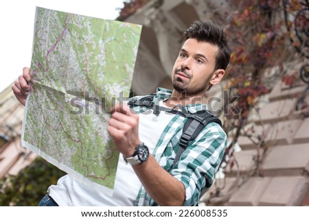 Beautiful young tourist man with a map of the city.