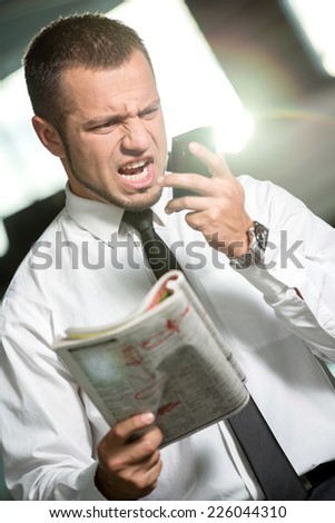 Unemployed man is looking for a job with newspaper and screaming into the phone.