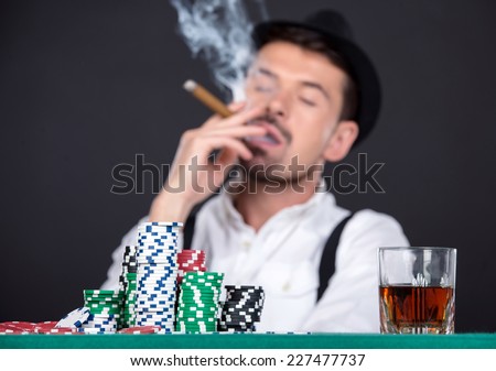 Man is playing poker in casino. Gambling chips, cigar and a glass of whiskey.