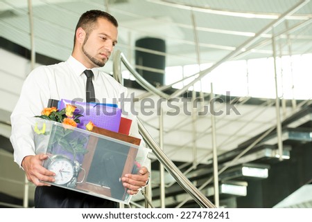 Fired businessman packed his bags and leaving office. He is looking sad.