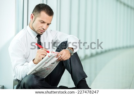 The concept of job search. A man is sitting with a newspaper.