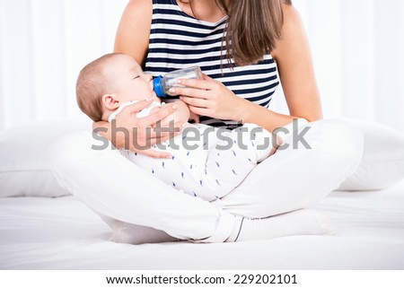 Portrait of a mother is  feeding her little baby boy from the milk bottle.