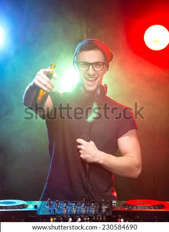 Portrait of a young dj with mixer, on foggy background.
