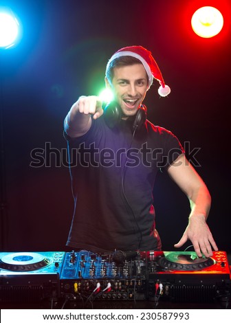 Portrait of a young DJ at work with a mixer, the club lights on the background.