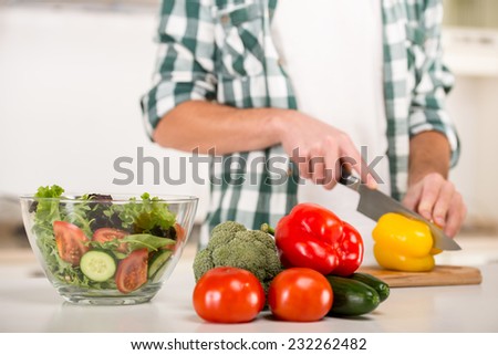 Man is cooking vegetable salad in the kitchen.