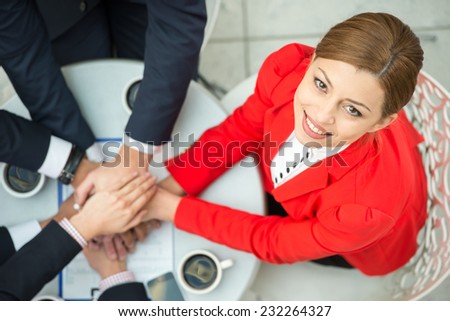 Top view of young woman at business meeting, while business team are showing unity with their hands together.
