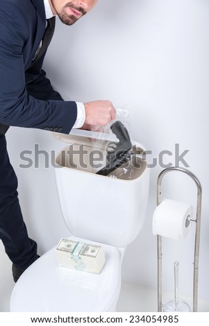Young man pulls gun from the toilet tank.