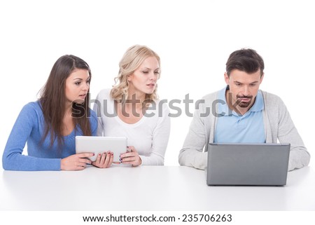 Man is looking at the laptop. Two young women are spying. White background.