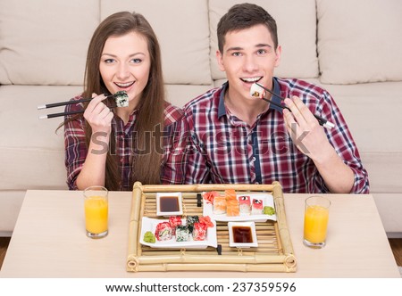 Couple are eating sushi. Beautiful young couple are sitting together, eating sushi and drinking juice.