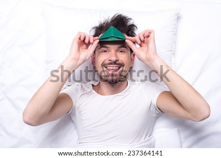 Top view of young smiling man with sleep mask in the bed.