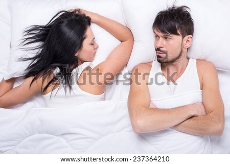 Young woman is sleeping in the bed. Husband is looking at her.