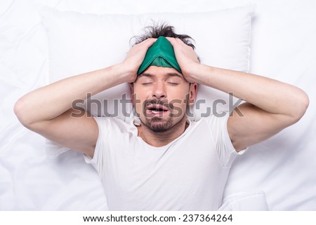 Top view of young sleepy man with sleep mask in the bed.
