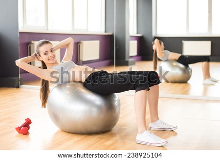 Sport, fitness, lifestyle concept. Smiling woman with exercise ball in gym is looking at the camera.