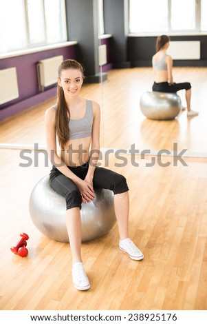 Sport, fitness, lifestyle concept. Smiling woman with exercise ball in gym is looking at the camera.