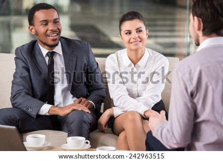 Group of smiling business partners are interacting in office during coffee break.