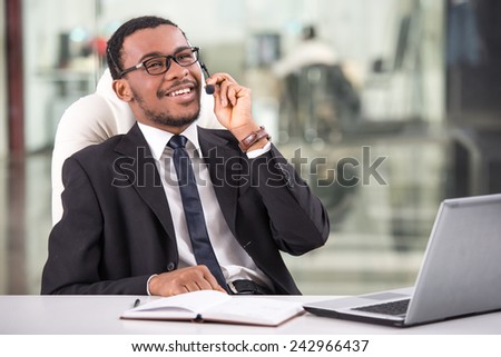 Handsome young businessman is taking a call on a headset as he deals with queries at the customer support call centre.