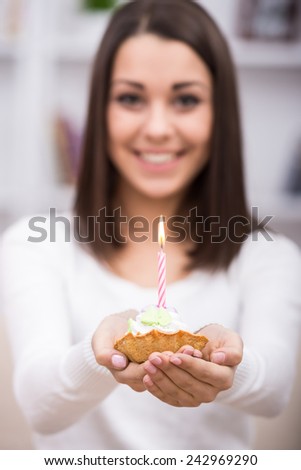 Close-up of birthday cake. Young woman is holding cake with candle.