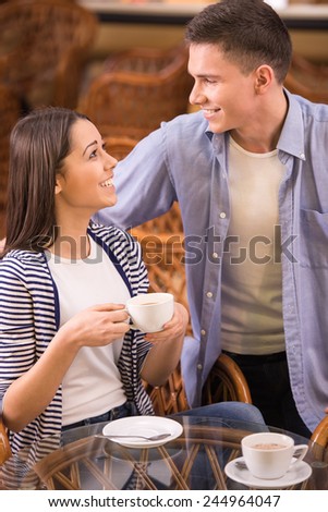 Young couple are sitting at the table and looking at each other.