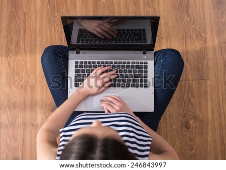 Top view of woman is using laptop while sitting on the floor at home.