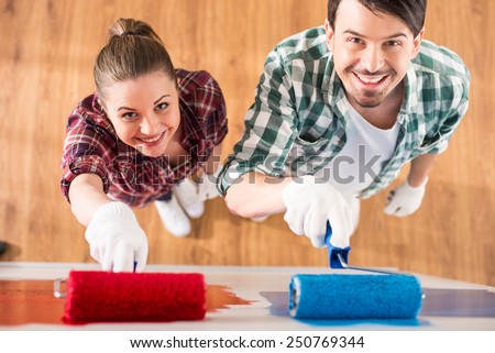 Top view of young couple are doing repair at home and painting a wall with roller.