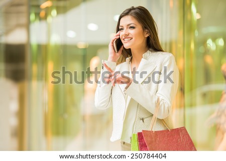 Beauty woman with shopping bags in shopping mall is talking by phone. Sales. Shopping Center.