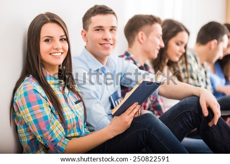 Education and people concept. Group of students are sitting on the floor with book.