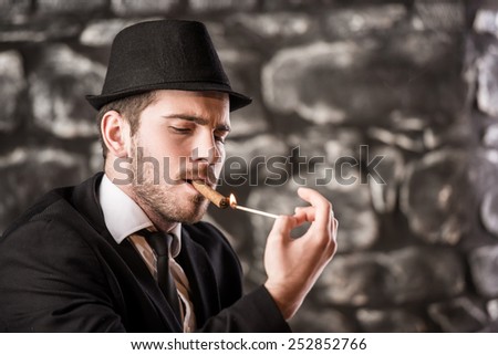 View of a gangster man is smoking a cuban cigar.