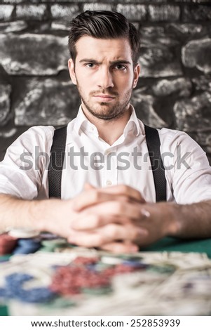 View of young, confident, gangster man in shirt and suspenders, while he\'s playing poker game.