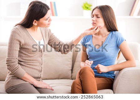 Mother and teen daughter after quarrel on sofa at home.