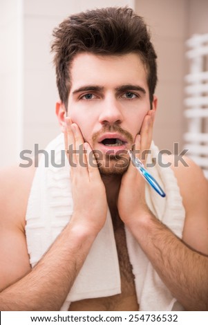 Morning routine of washing the teeth. Tired young man is brushing teeth with toothbrush.
