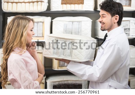 The young salesman tells the customer about quality mattresses in the store.