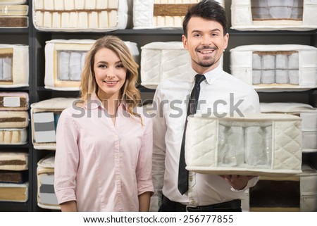 Good choice. The young salesman and the customer with quality mattresses in the store.